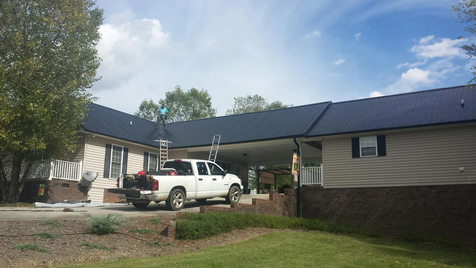 Black metal roof over a home and attached breezeway with ladders set in Richfield