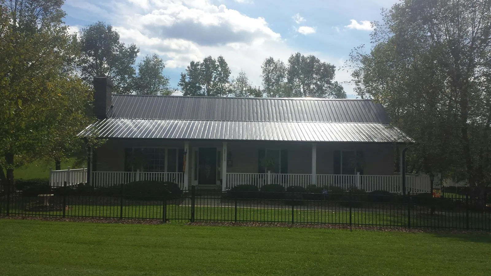 Gray metal roof on a brick ranch with a full width front porch — Gutter Guard Installation work by our crew in Richfield